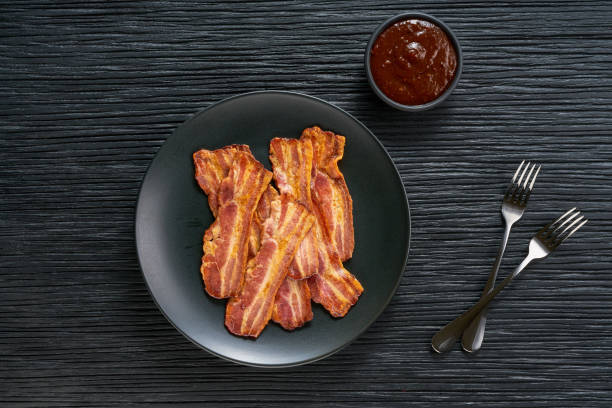 istock fried bacon with bbq sauce in a dish on a black table, top view. 1487183248