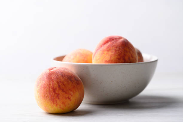 istock Ripe Peaches fruit in bowl on white table 1487186511