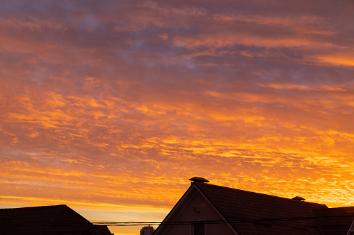 orange sunset. orange sky at sunset against the background of the roofs of houses