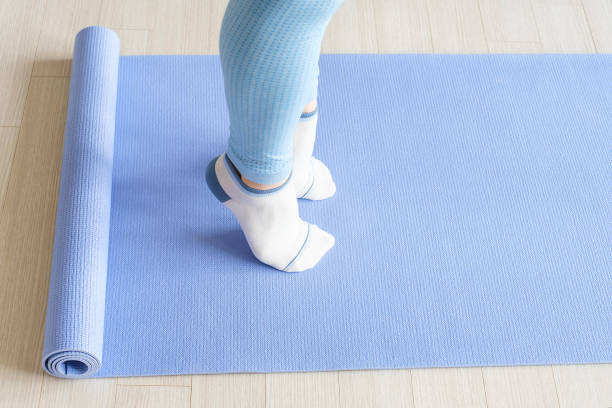 Female legs doing exercises lifting on toes close-up on blue background.