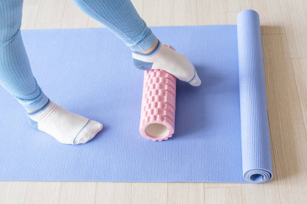 istock Female foot rolls a massage foam roller close-up on a blue background. 1487199583