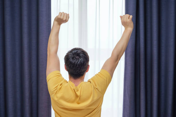 Man stretching in morning and open curtains, early wake up concept. stock photo