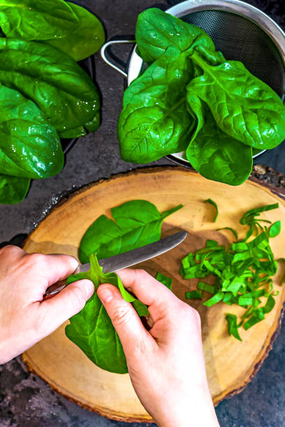 istock A woman is cutting fresh spinach on a cutting board 1487203845
