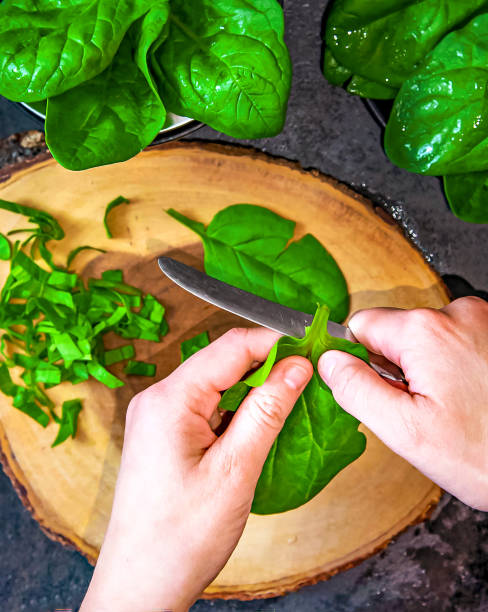 istock A woman is cutting fresh spinach on a cutting board 1487203893