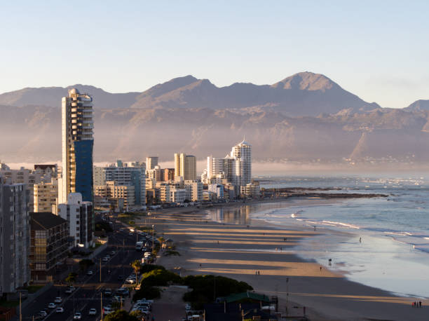 Early morning shot over Strand Beach near Cape Town. Aerial shot over a beachfront with early morning sunlight casting shadows from the buildings on the beach. Strand beach near Cape Town early in the morning. gordons bay stock pictures, royalty-free photos & images