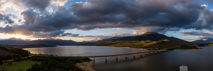 Sunlight casts over a bridge which crosses a large lake. Bridge crossing over the Theewaterskloof dam in the Western Cape, South Africa