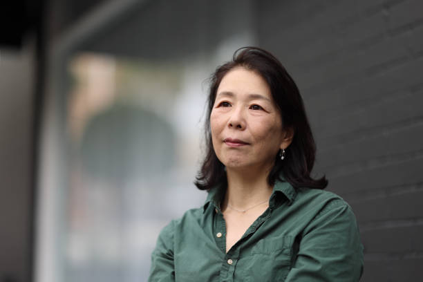 istock Japanese woman outdoors looking off camera with a building wall behind. 1487206486