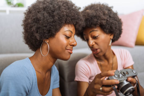 Twins with afro hairstyle, talking about the antique camera, sitting on the living room floor