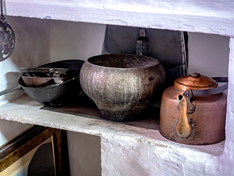 an old copper kettle and cast-iron utensils on the stove, authentic things