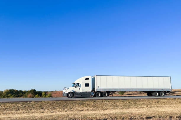 istock White Conventional Cab-Forward Semi Truck Driving West on Interstate 70 West across Kansas on a Sunny Day 1487212495