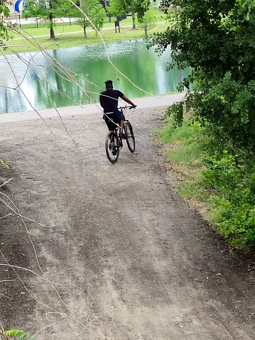 Overhead View of Young Male Riding Bike on park trail near pond