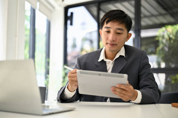 istock A focused Asian male boss using his tablet to manage his tasks at his office desk. 1487220367