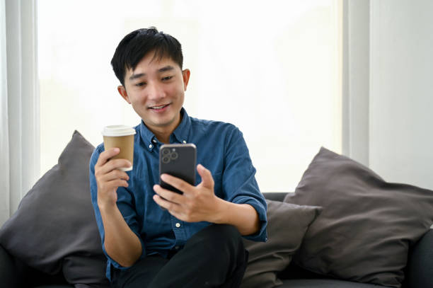 istock An Asian man enjoying his coffee while scrolling on his phone at a living room. 1487220446