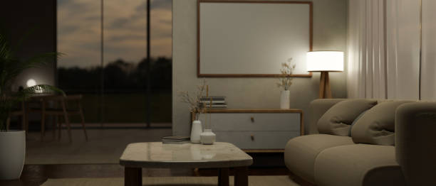 istock Comfortable living room at night with cozy couch, coffee table, blank frame mockup on wall 1487220493