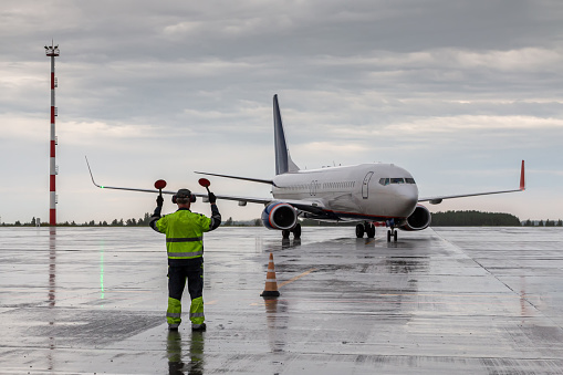Aircraft marshalling at the aiport apron in rainy weather. Passenger airplane meeting at Chelyabinsk airport