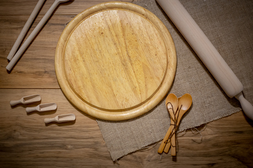 Wooden kitchen accessories: plate, rolling pin, board, spatula on a concrete background. Top view. Kitchenware.