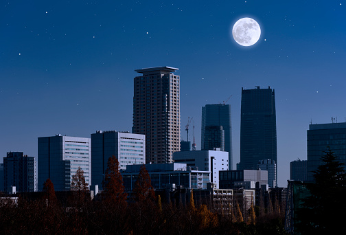 Full moon rising over the skyscrapers against clear sky with copy space.