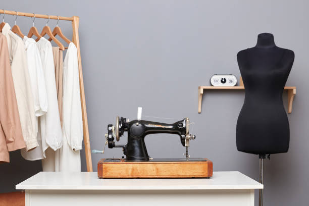 istock Workplace with sewing machine on table, mannequin with new dress, hanger with sewn clothes. 1487230335