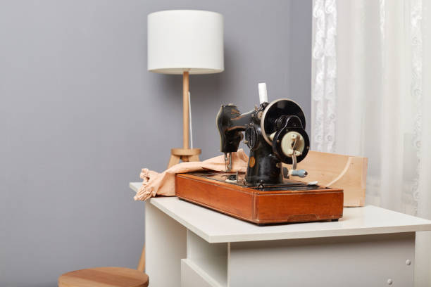 istock Tailor's workplace with sewing machine and clothing on table in atelier, tailoring workshop, empty space for advertisement. 1487230353