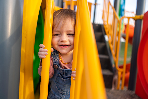 Portrait of a happy little girl playing on the playground during spring day