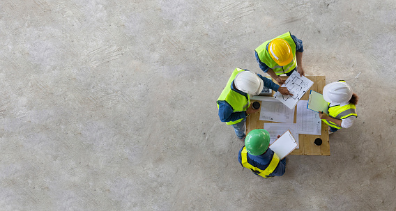 Top view of engineer, architect, contractor and foreman are meeting at the construction building site with floor plan for real estate development project industry and housing timeline usage