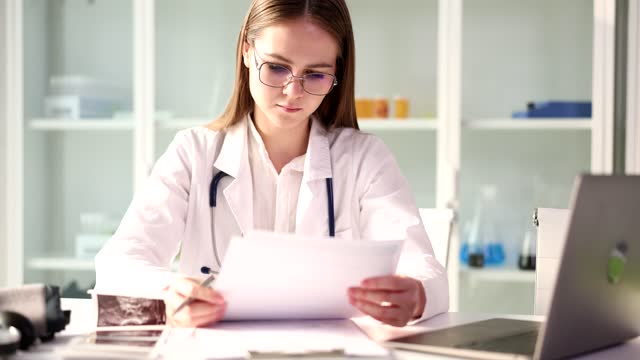 Focused medical doctor student looks through paper documents and reads health insurance contracts