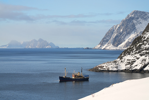 A fishing boat sails in the extreme south of the Lofoten Islands. In the background are the hilly islands of northern Norway.