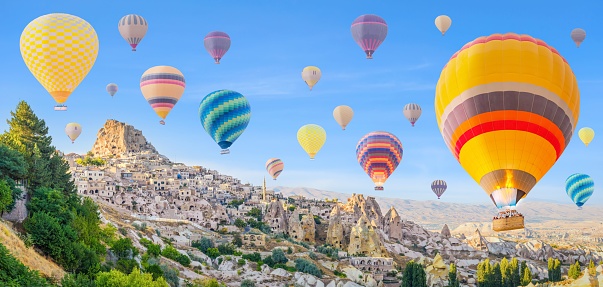 A scenic aerial view of hot air balloons floating in the sky at sunset in Goreme, Cappadocia, Turkey