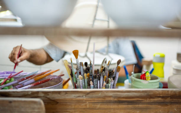 istock Set of various paint brushes and drawing tools for ceramic pottery decoration on workbench 1487243974