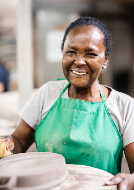 istock Senior female worker making ceramic pan on potter's wheel in a workshop 1487244215