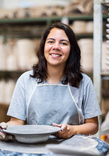 istock Happy mature woman making ceramic plate on potter's wheel in a workshop 1487244847