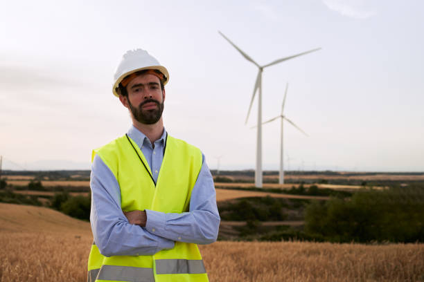 istock Technical engineer poses confidently with arms crossed looking at camera standing in a wind farm. 1487247060