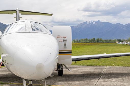 A private jet plane is parked on the tarmac waiting for the customers.