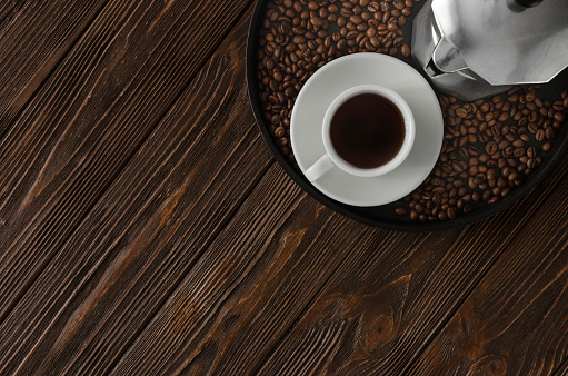 Black coffee in white cup, with coffee beans on wooden background, top view, copy space