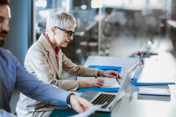 istock Senior businesswoman taking notes in the office. 1487249333