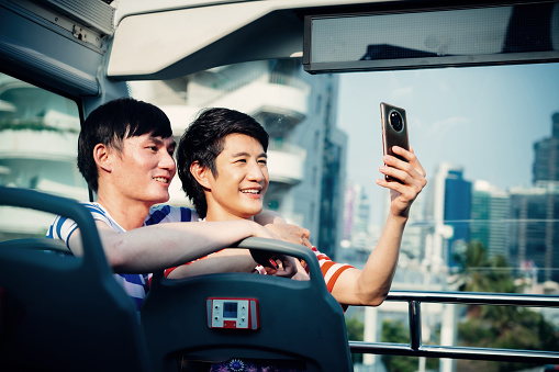 Candid portrait of smiling gay couple taking selfie on coach