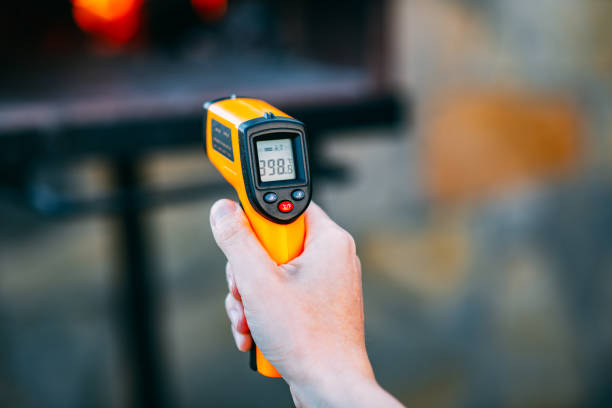 infrared thermometer measures the temperature of the oven - infrared thermometer imagens e fotografias de stock