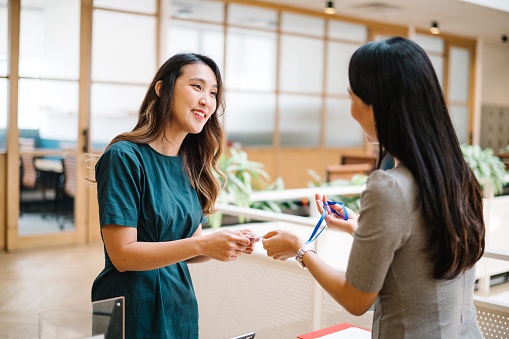 Asian Chinese businesswoman is passing name tags to her attended