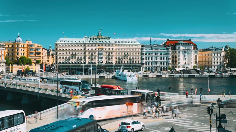 Stockholm, Sweden. Traffic With Cars And Buses. Touristic Pleasure Boats Floating Near Famous Grand Hotel In Sunny Summer Day. Grand Hotel Located On Peninsula Blasieholmen. Travel to Sweden