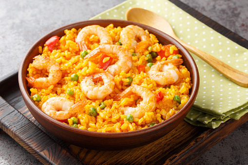 Yellow rice with shrimp with some addition of vegetables and spices close-up in a bowl on the table. horizontal