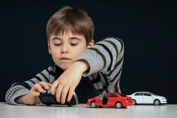 istock Elementary age boy plays with toy cars on the table 1487263772