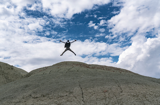 man jumping in the mountains against the blue sky. nature and human big advertising space