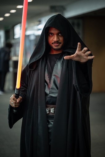 Cape Town, South Africa – April 29, 2023: A person dressed in a Darton costume is standing with illuminated lightsabers in their hand