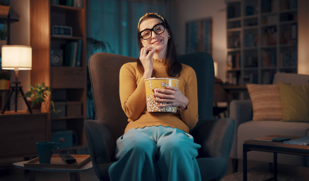 istock Expressive woman watching TV and eating popcorn 1487267980