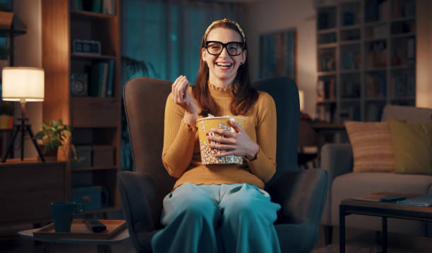istock Expressive woman watching TV and eating popcorn 1487268037