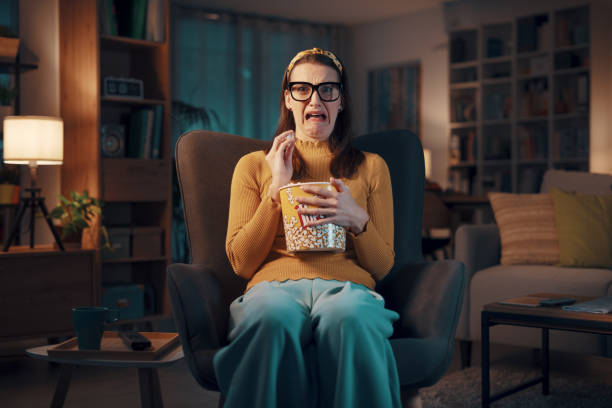 istock Expressive woman watching TV and eating popcorn 1487268113