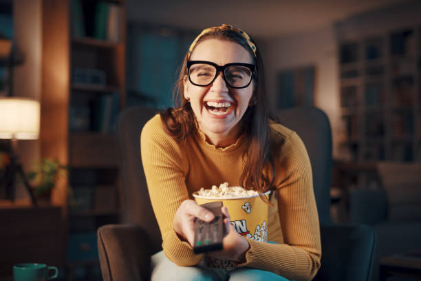 istock Expressive woman watching television and holding the remote control 1487268551