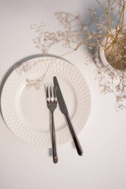 istock White ceramic plate with a stainless steel fork and a knife next to a plant. 1487268654