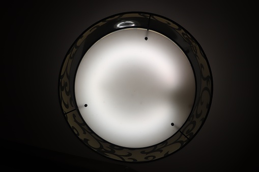 A round light fixture mounted on a wall illuminated with a bright glow
