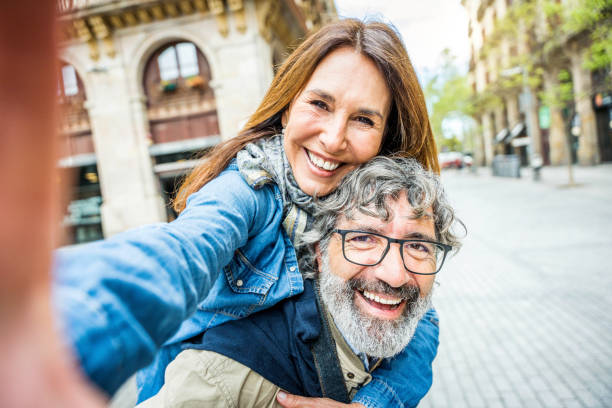 älteres paar macht selfie mit smartphone drau�ßen - zwei ältere touristen genießen zusammen sommerferien - lifestyle-konzept mit reifen frauen und männern, die in die kamera lächeln - women telephone senior adult on the phone stock-fotos und bilder